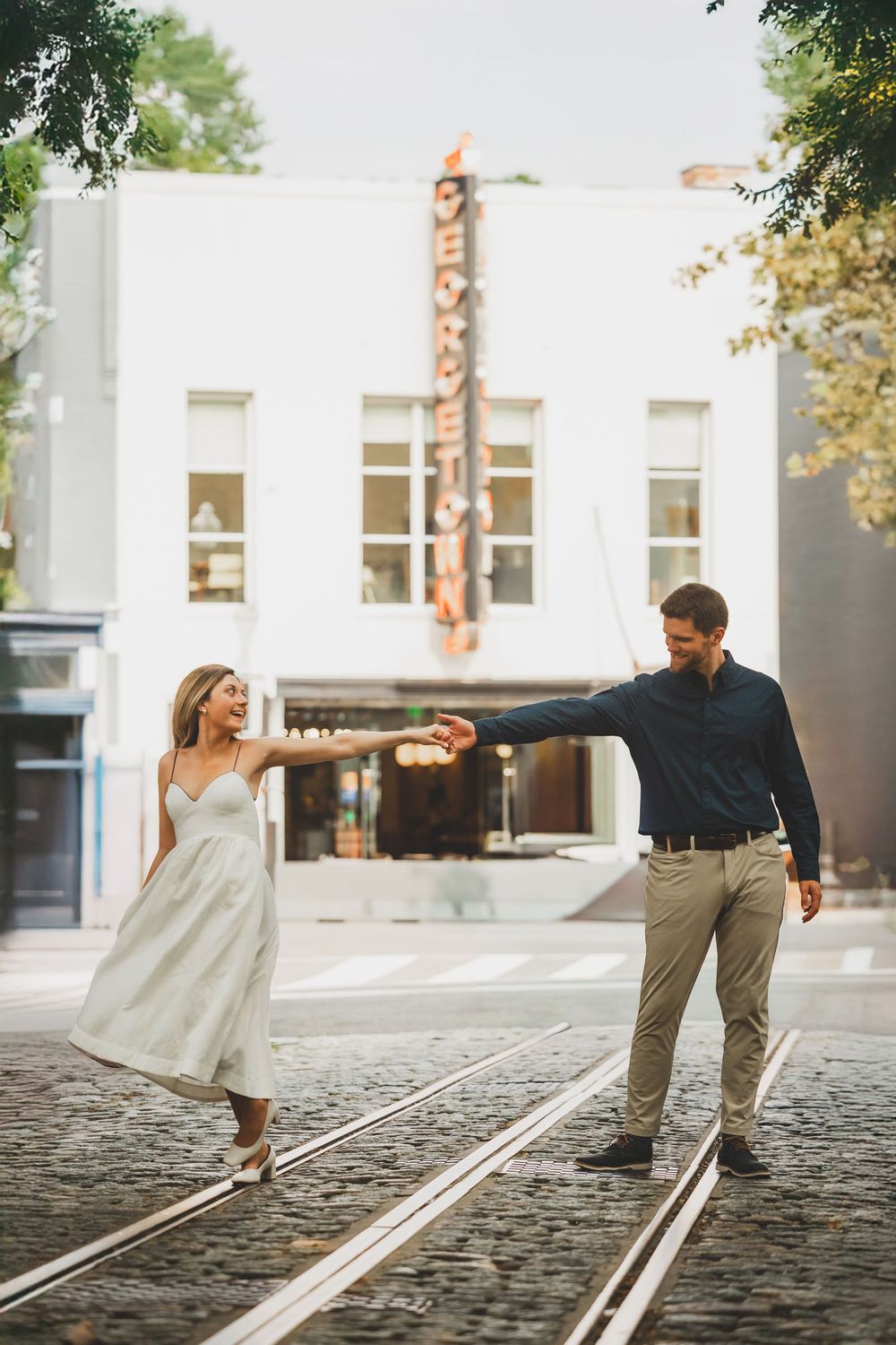 A couple dances playfully together on a cobblestone street, creating a series of romantic movement shots.