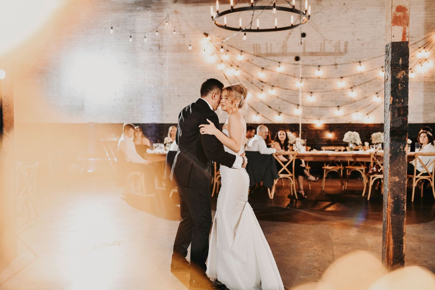 Bride and groom sharing their first dance under modern uplighting at Brake & Clutch Warehouse