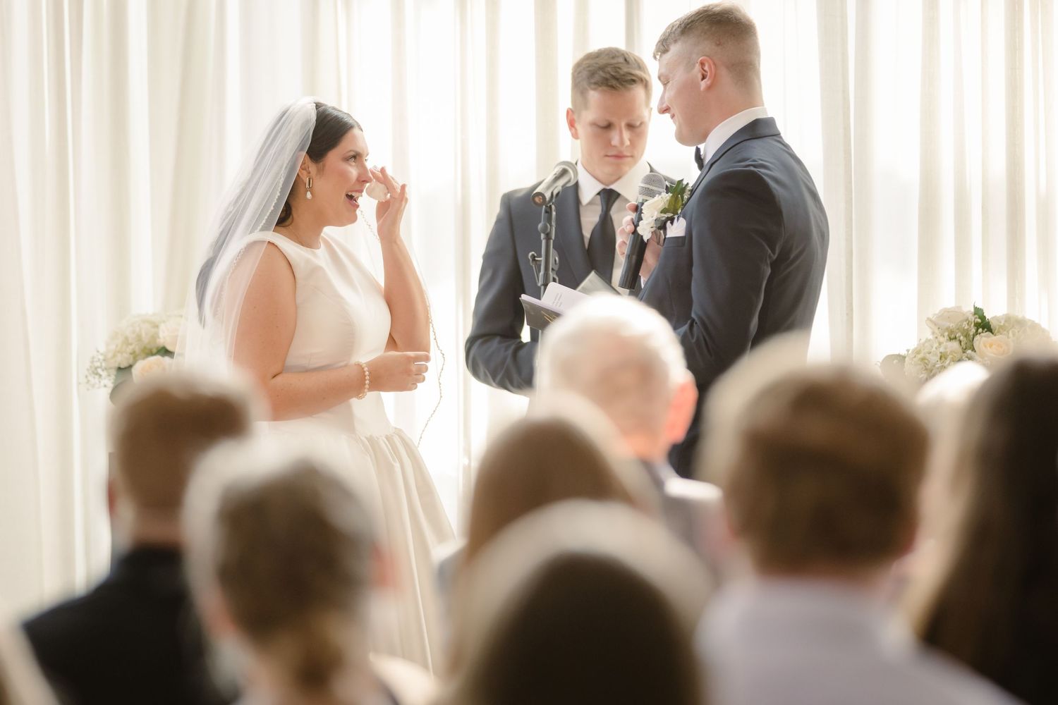 A wedding ceremony in progress with guests seated in rows watching the couple exchange vows at the altar.