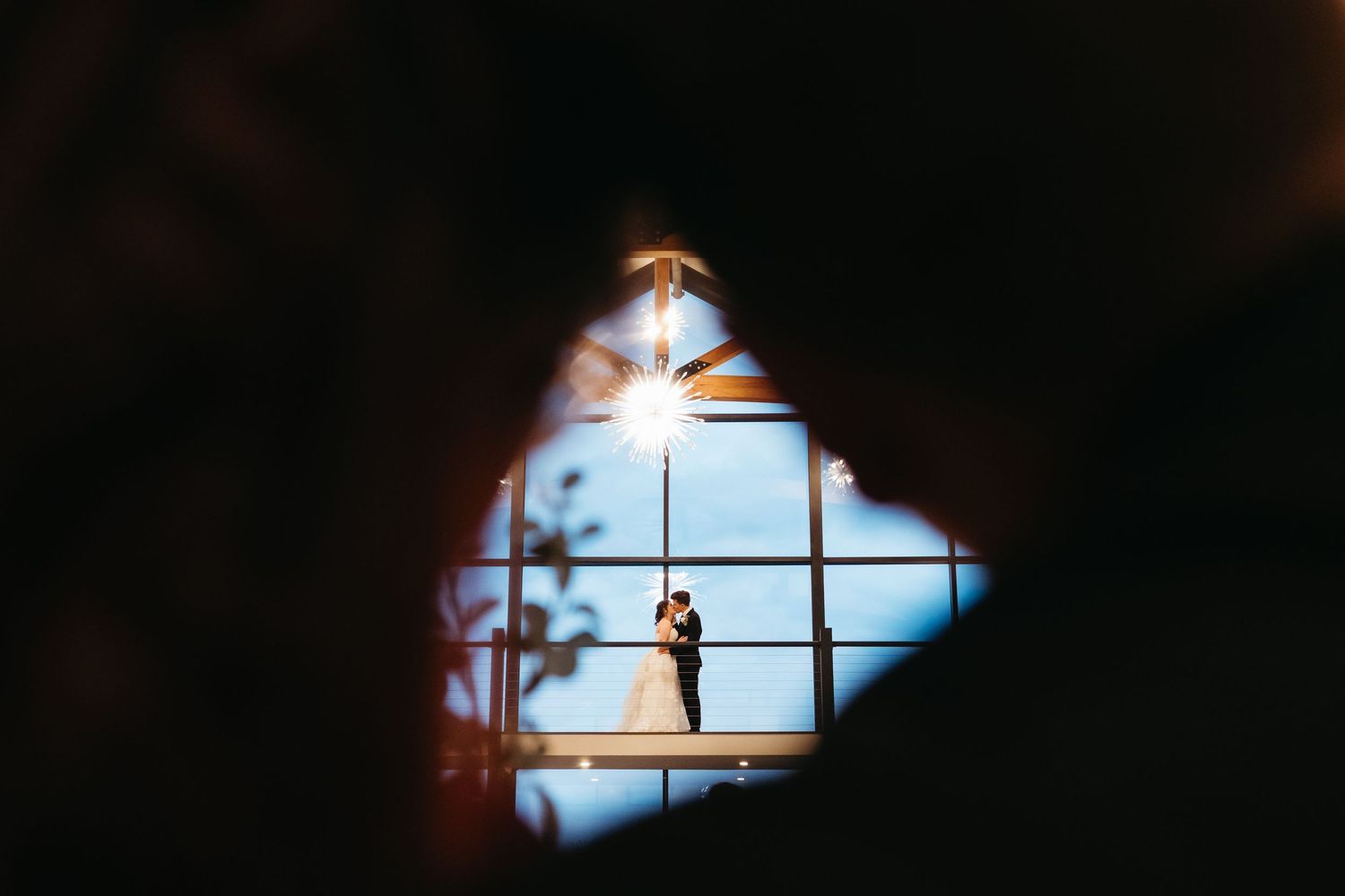 A series of seven silhouetted crucifixes against a bright blue sky seen through window frames.