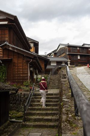 Stone steps and wooden buildings line a historic street in a traditional Japanese mountain village.