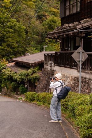 People taking photographs along a traditional Japanese stone wall and building path.