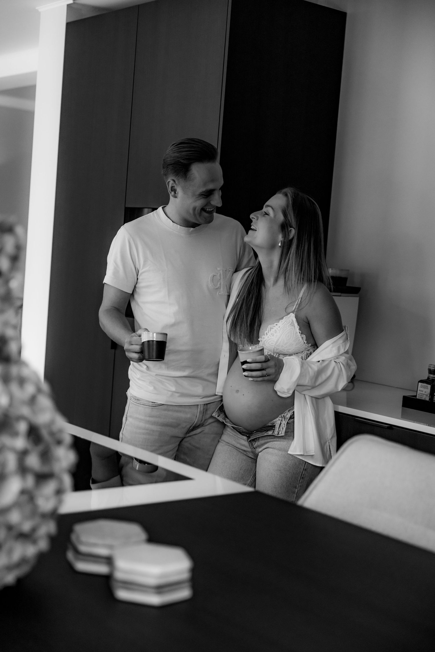 Black and white photos of couple sharing intimate moments in kitchen setting.