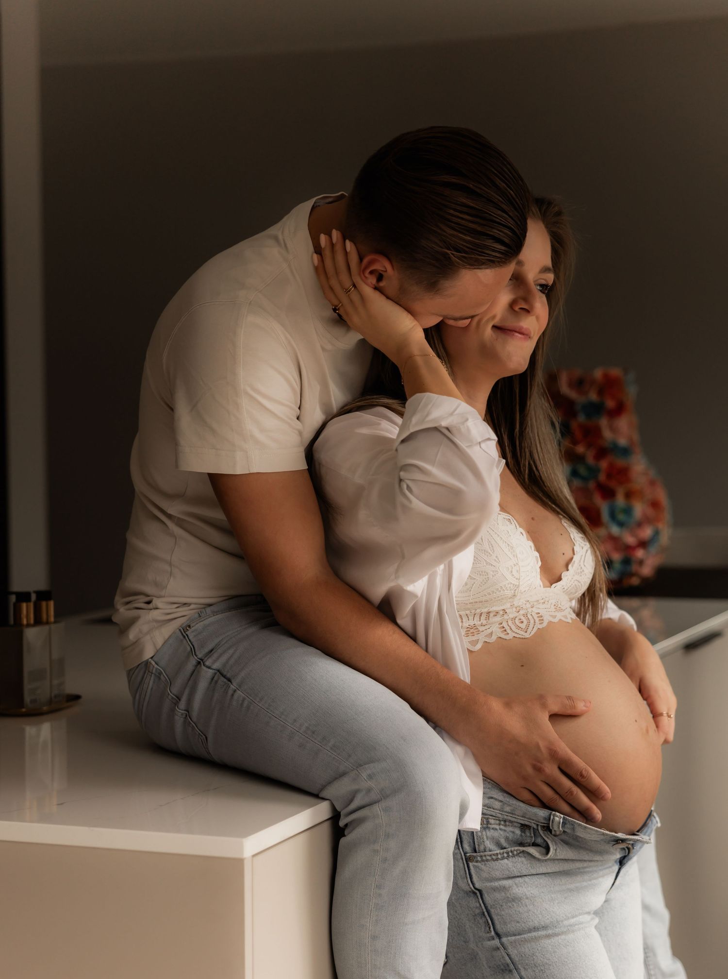 Intimate maternity photography session capturing tender moments in soft lighting.