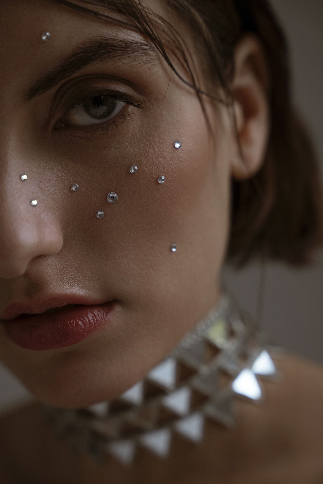 Artistic beauty portrait with crystal embellishments and dramatic lighting.