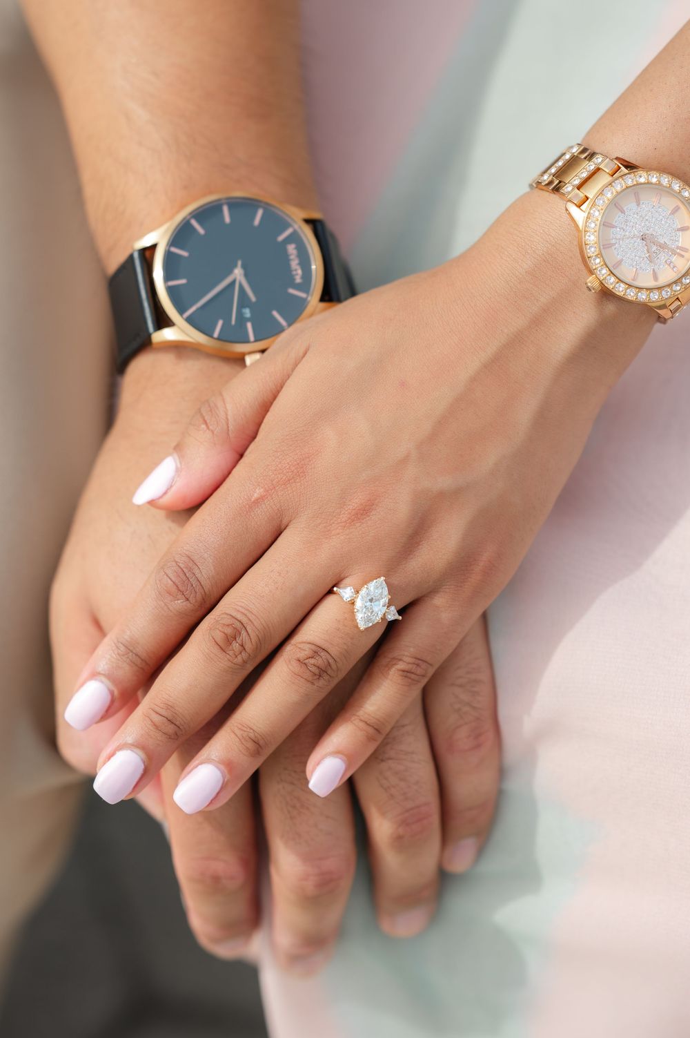 Close-up view of a sparkling solitaire diamond engagement ring on a manicured hand with pink nail polish.