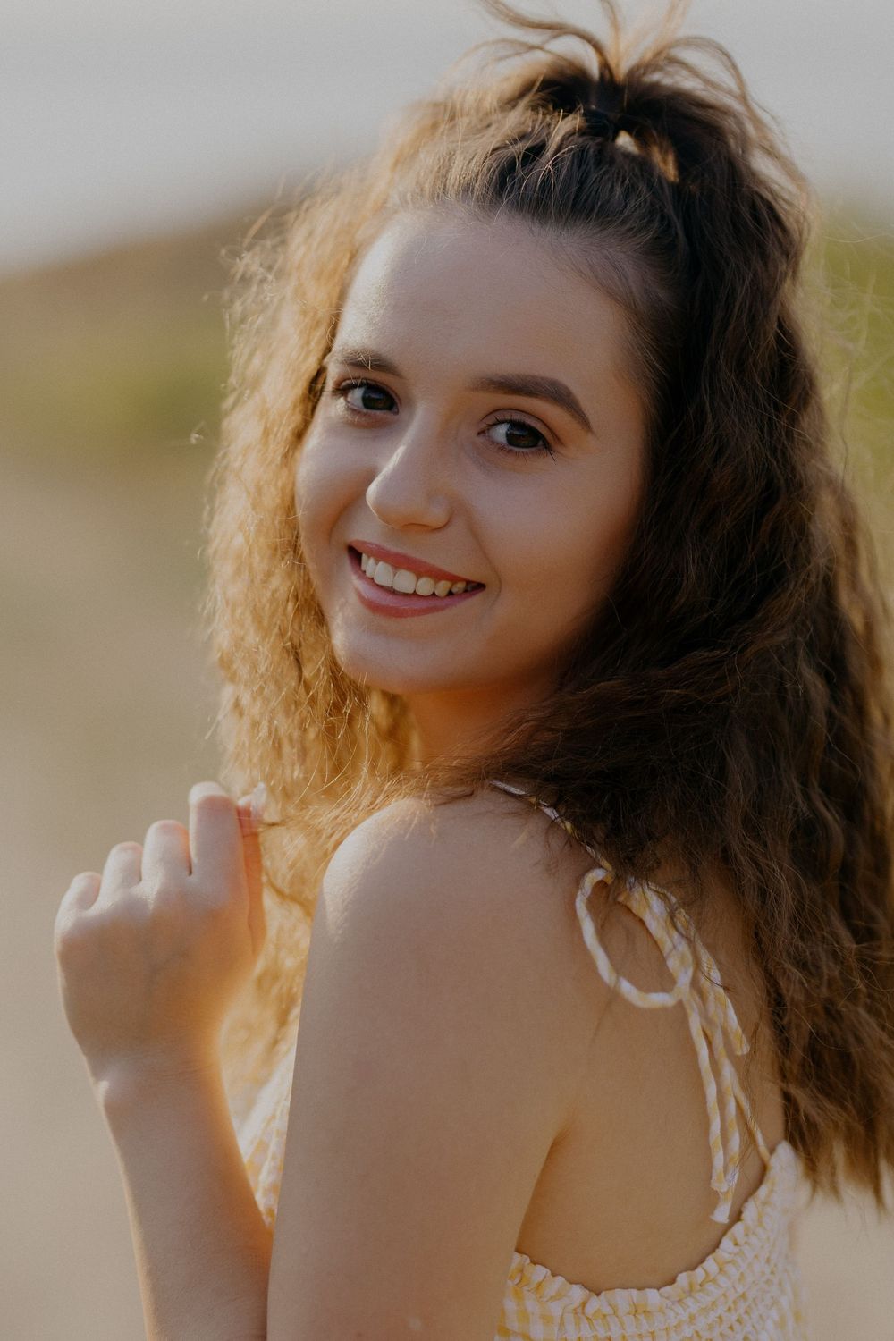 A series of candid portraits showing someone with curly hair smiling and posing outdoors in natural lighting.