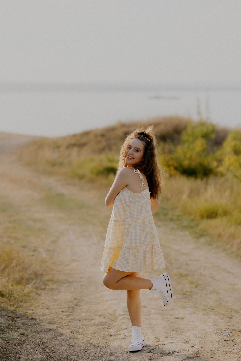 A figure in a white dress dances and twirls along a sunlit dirt path in a series of artistic motion shots.