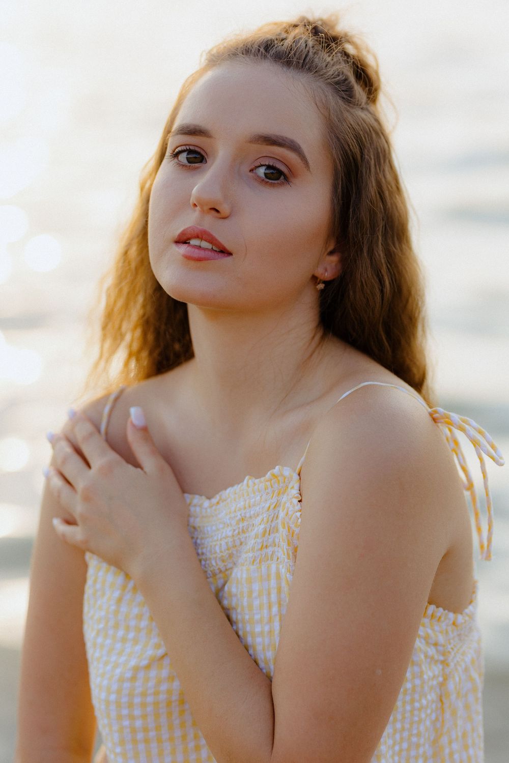 A golden hour portrait features someone in a gingham dress against a soft blurred background.