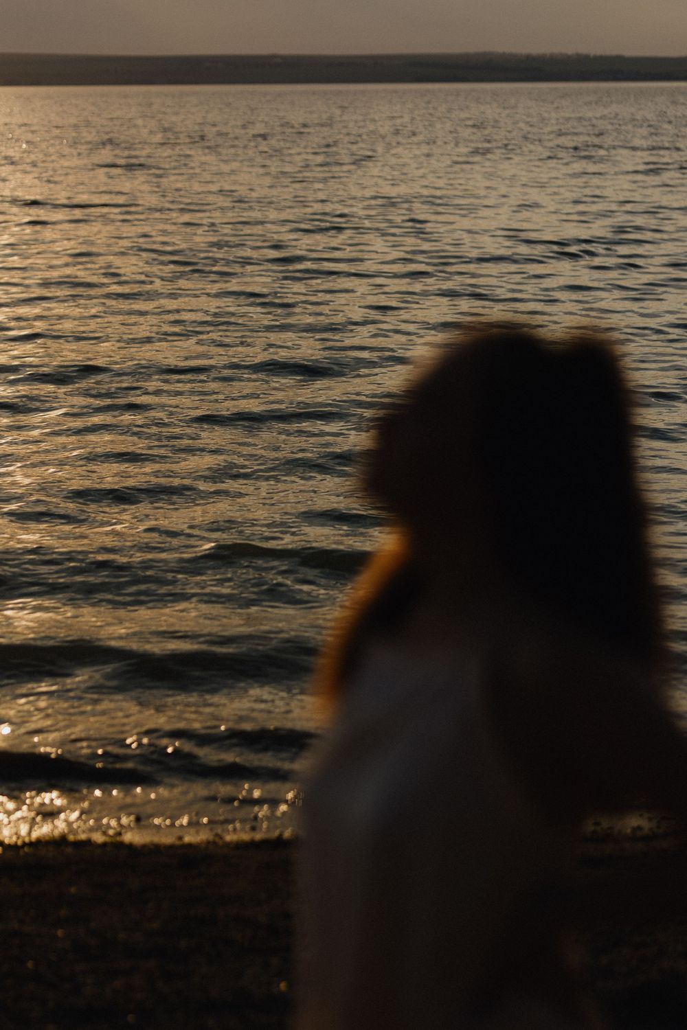 Silhouetted waves sparkle at sunset with dark shapes in the foreground.