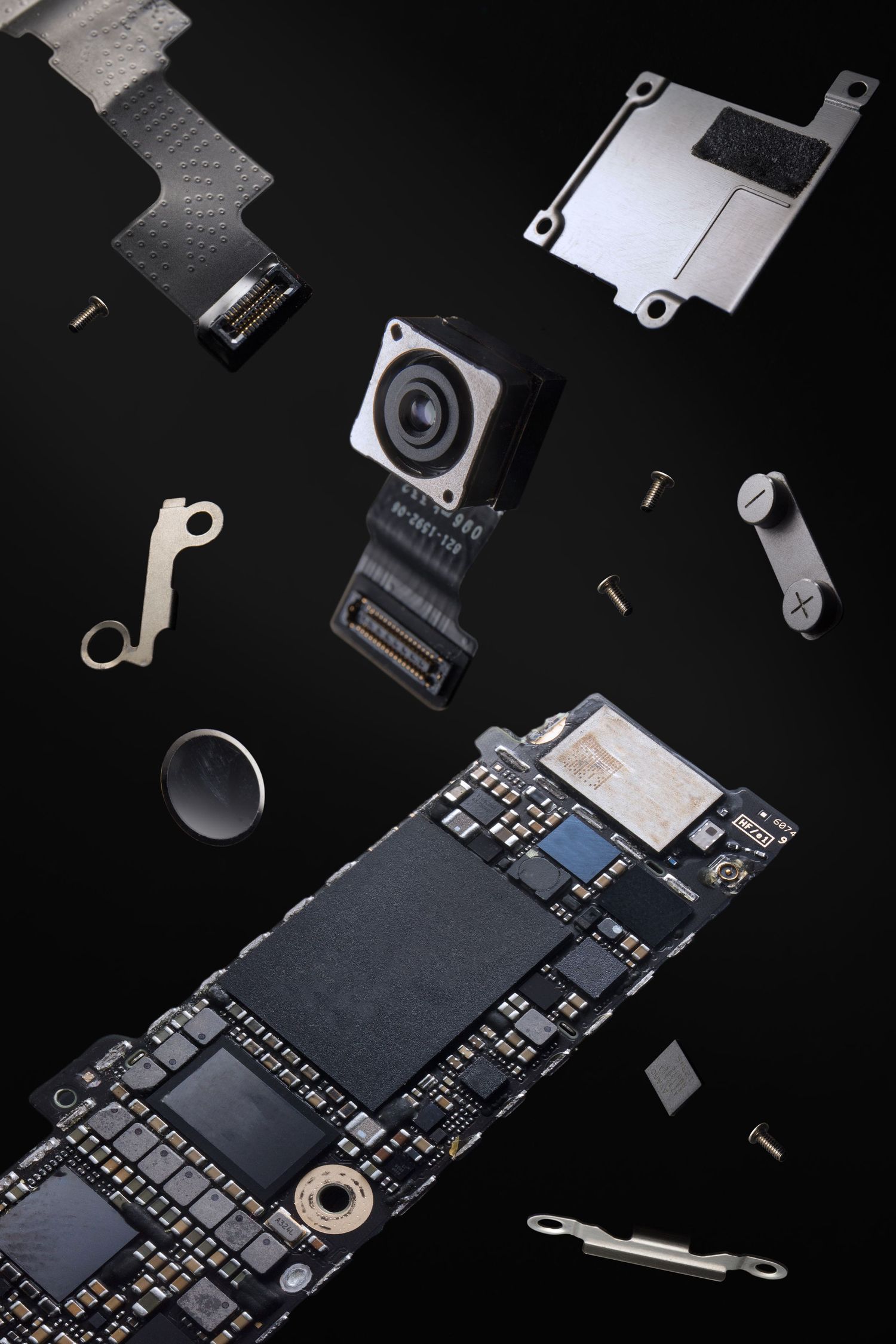 Disassembled smartphone components and circuit boards on black background.