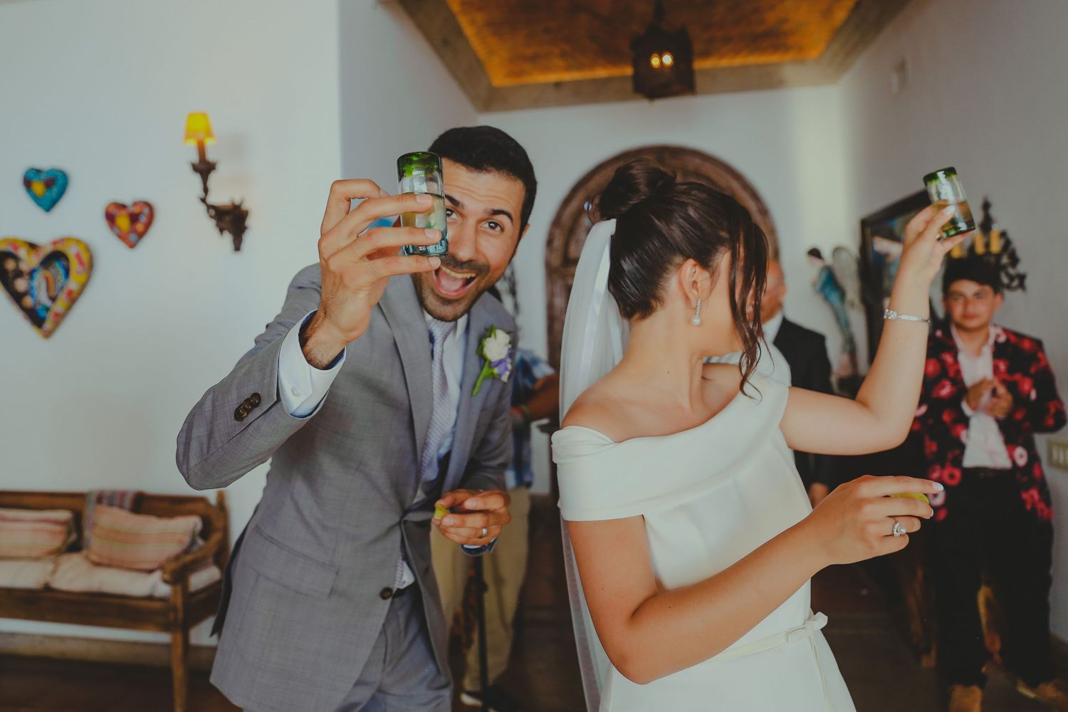 People dancing and celebrating at a party with drinks in hand while wearing formal attire.Pedregal Los Cabos Wedding Photographer
