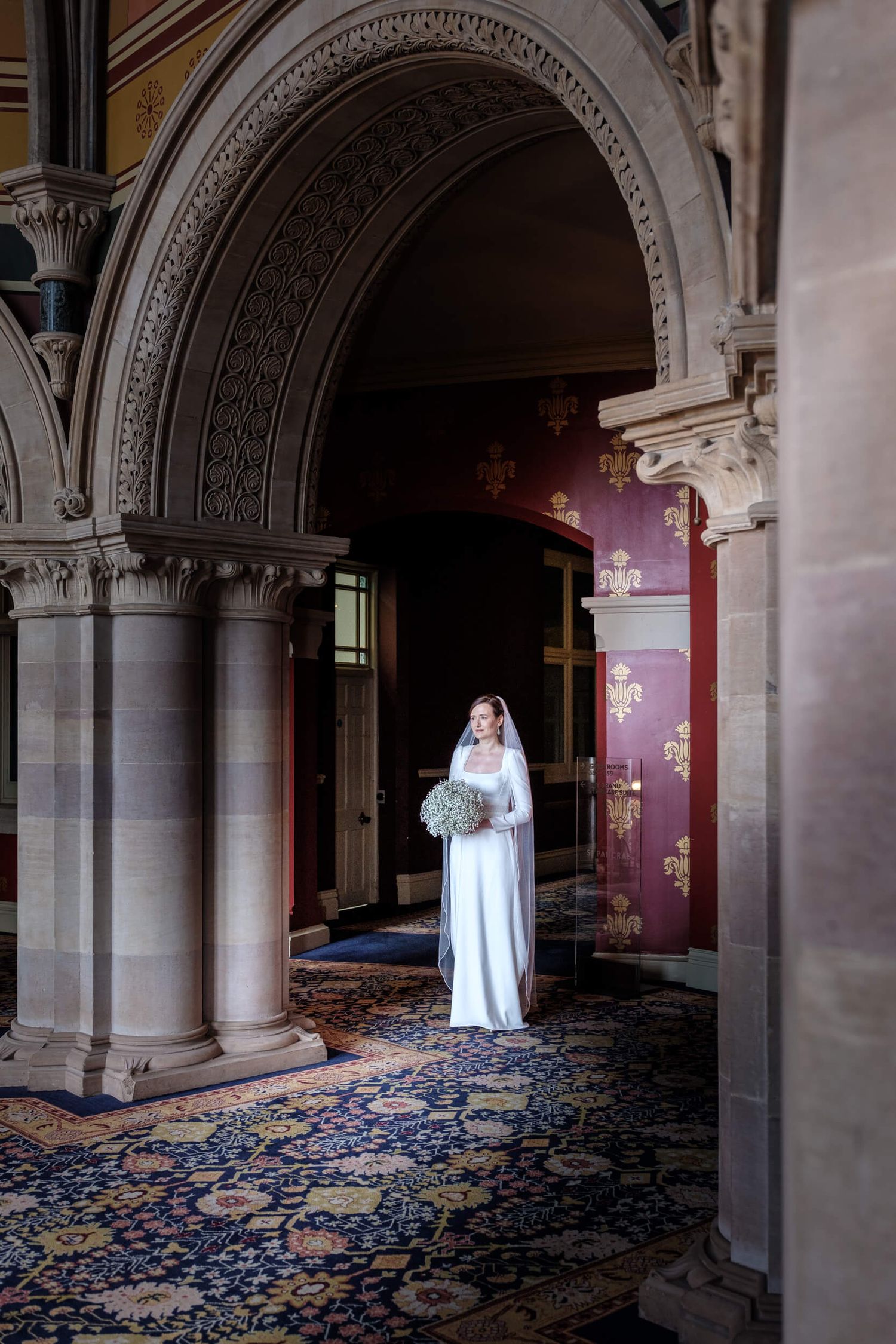 A ghostly figure in white stands in an ornate hallway with arched columns and blue patterned carpet.