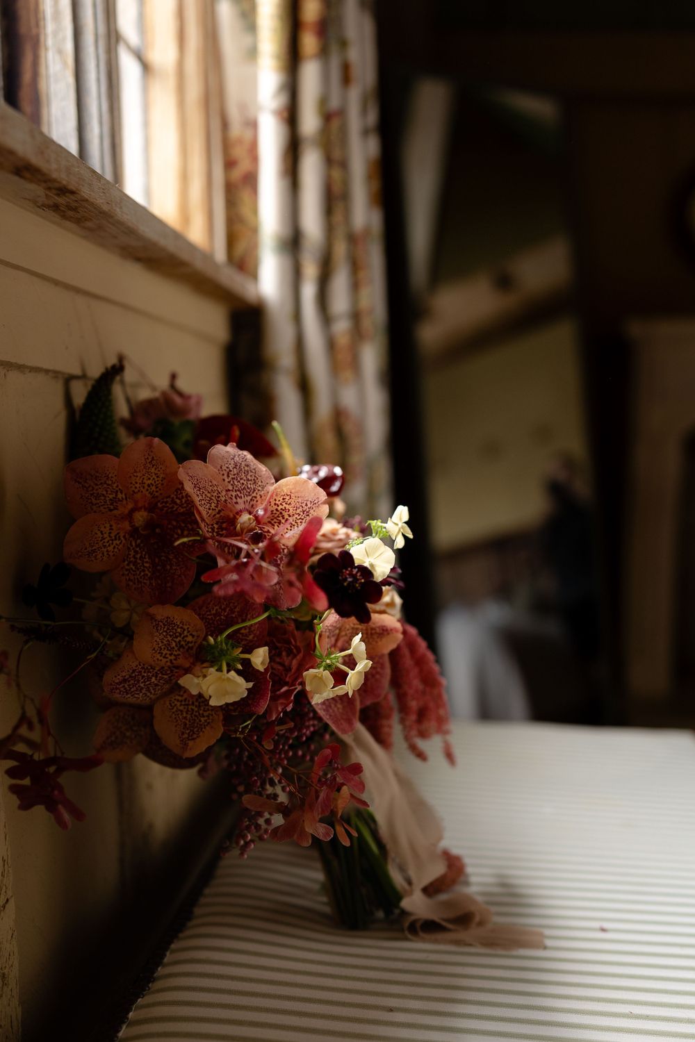 Romantic burgundy and pink wedding bouquet by window in natural light.