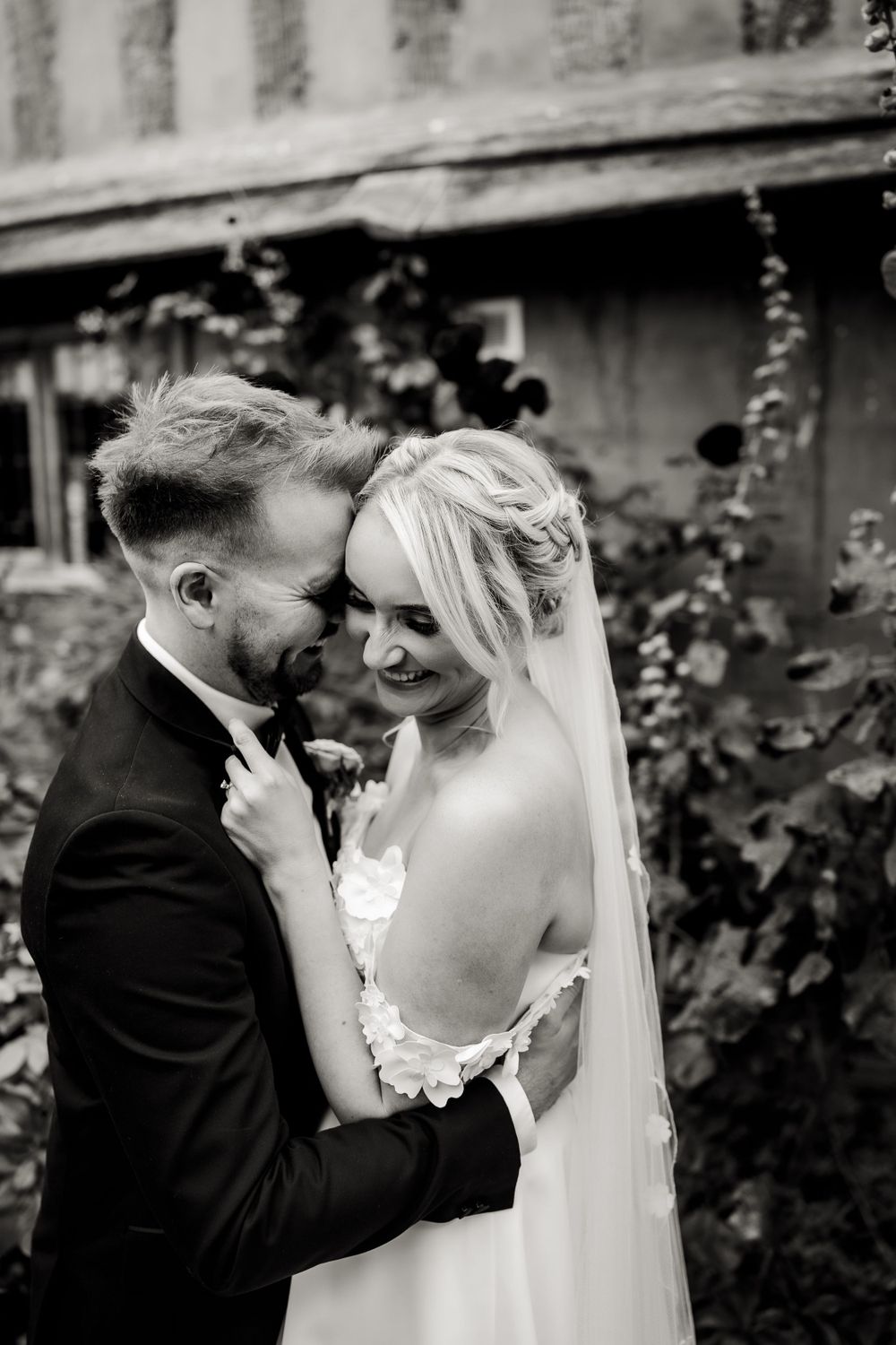 Classic black and white portrait of a tender wedding moment with flowing veil.