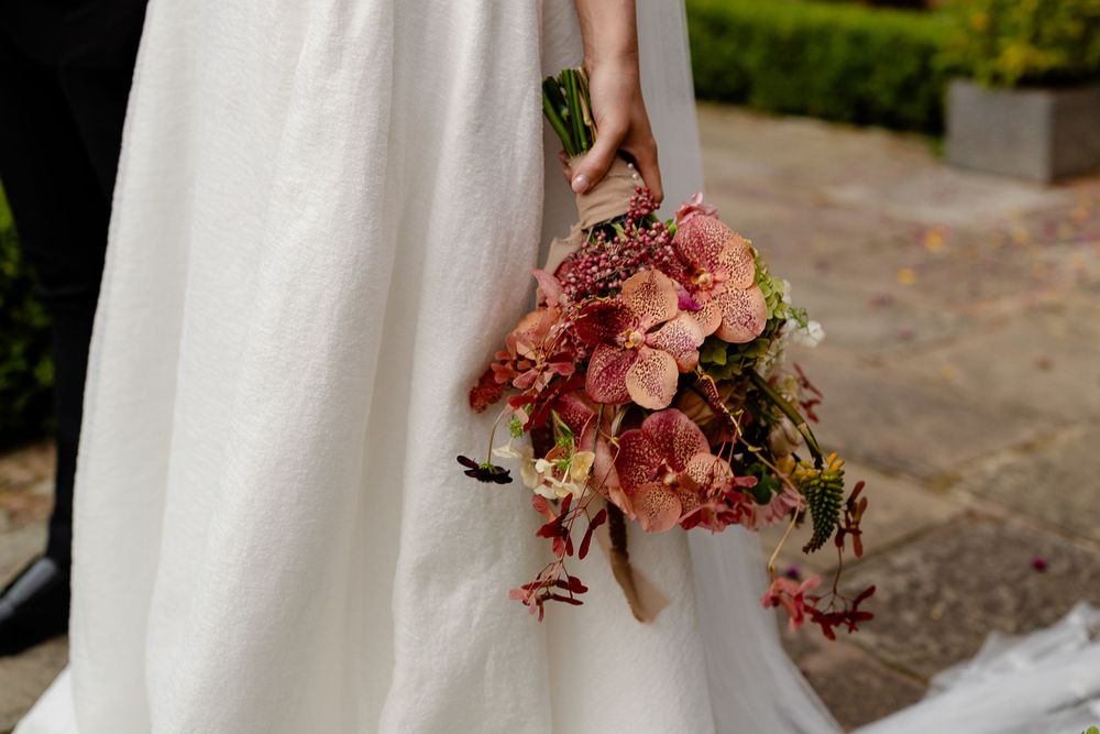 Close-up of a romantic pink and peach bridal bouquet against a white wedding dress.