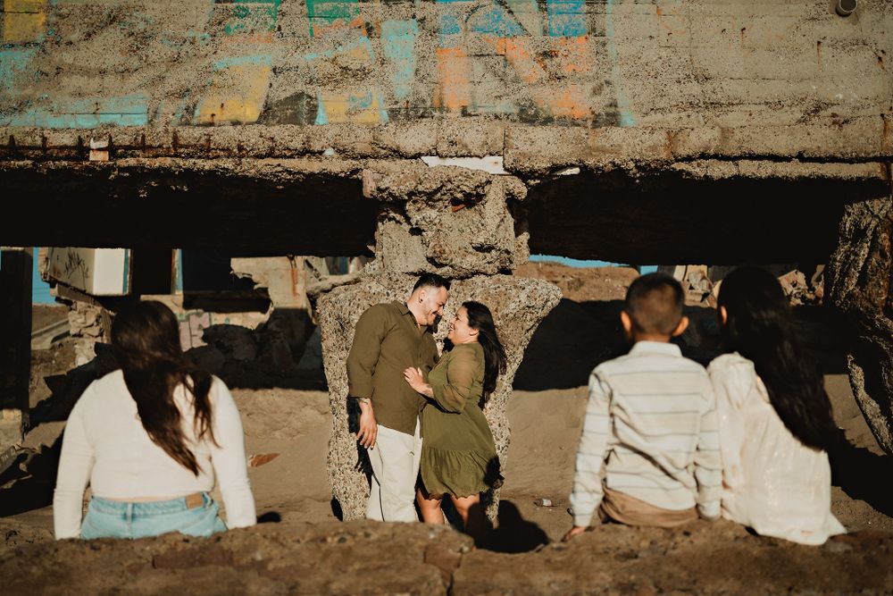 Children looking at their parents sharing a romantic moment on the coast