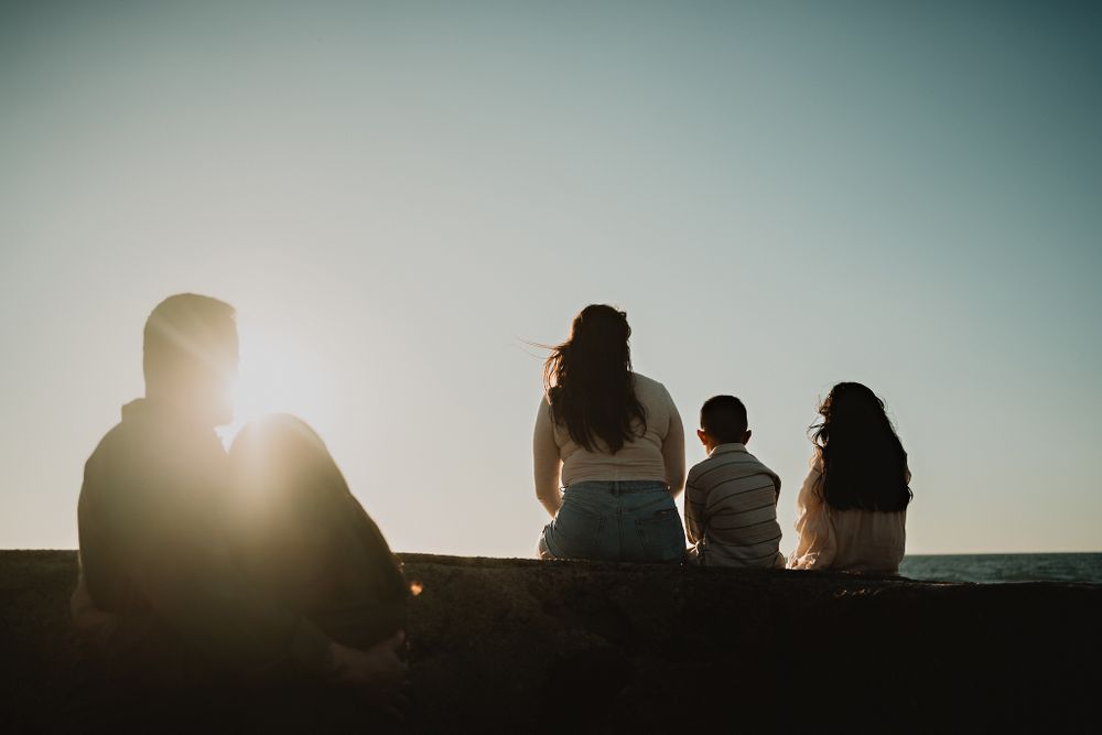 Parents embracing while watching their children play in the sand