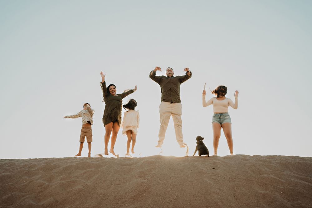 Family jumping in the sand with their pet, having fun in the Mazatlán sun