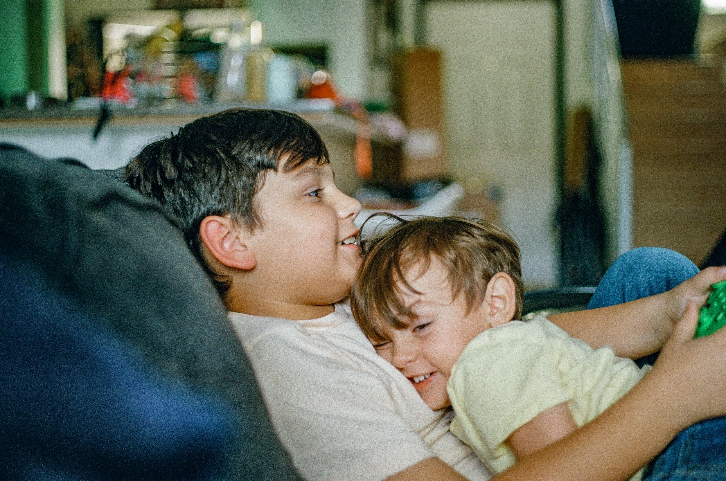 Two young individuals relaxing together on a couch in a casual home setting.