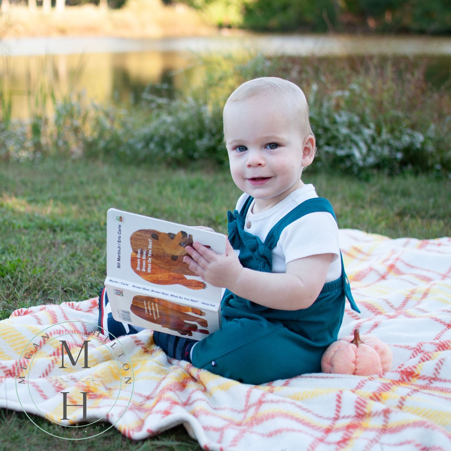 toddler reading book by pond photo