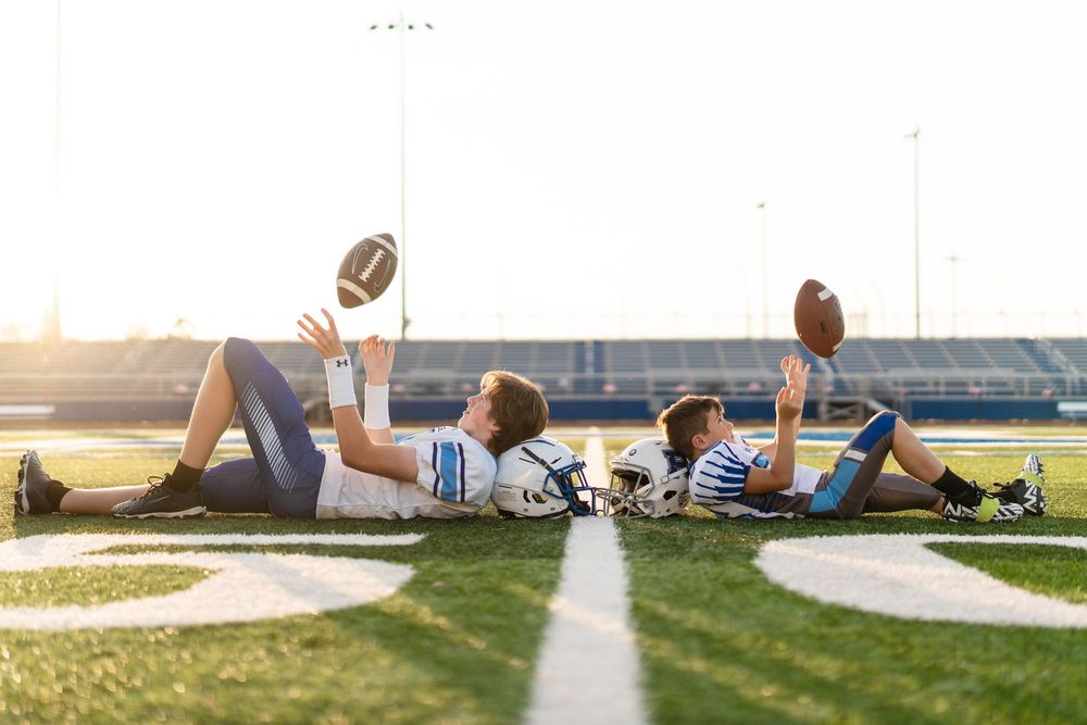 A football soars through the air against a bright blue sky during a game or practice session.