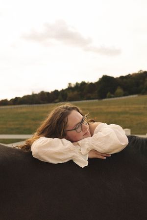 Person resting peacefully in white clothing against dark surface with scenic rolling hills in background during sunset.