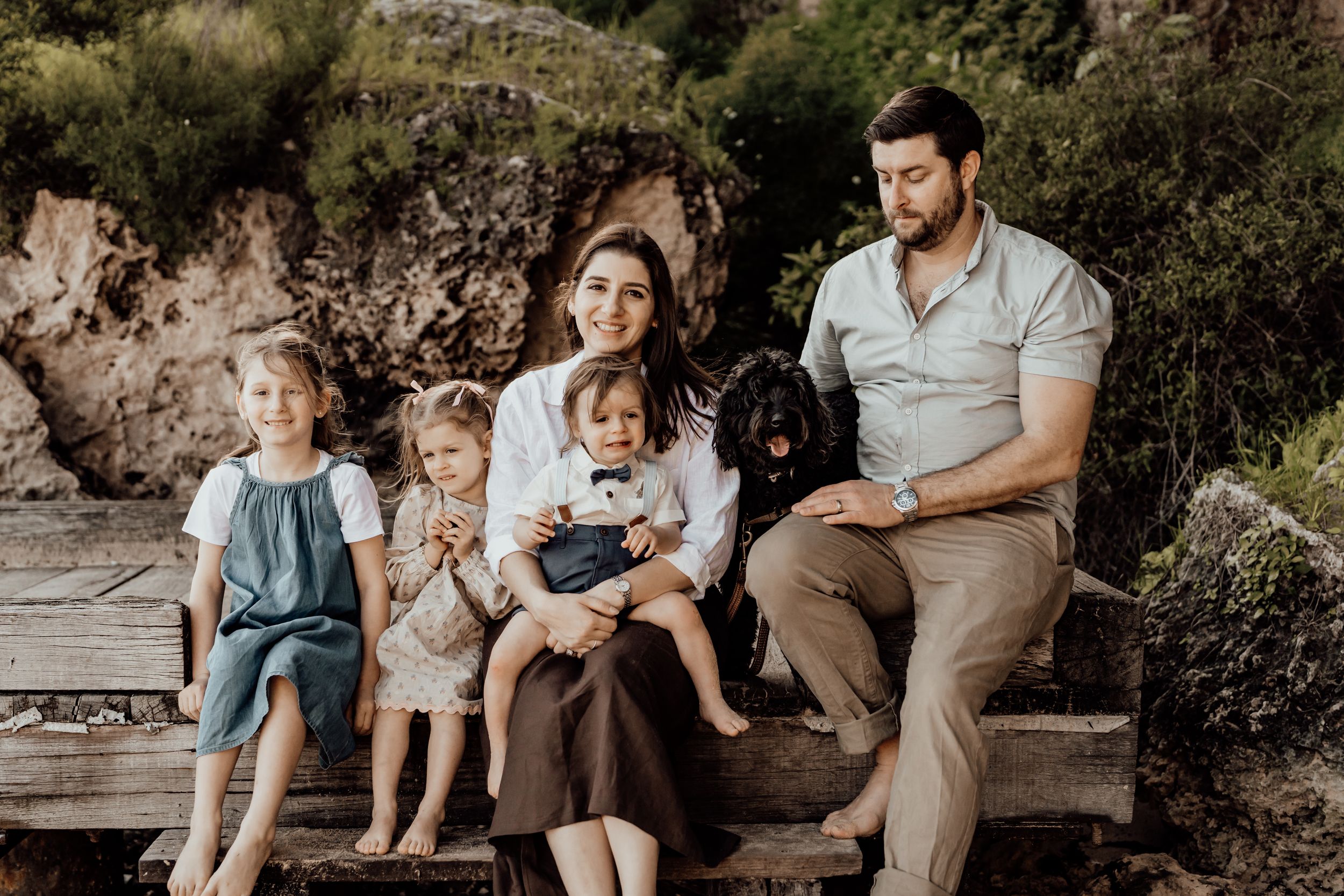 Extended family relaxing together on wooden seating in a park setting.