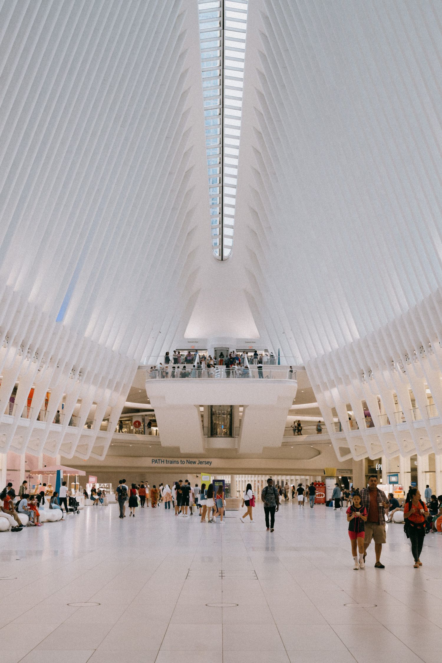 Striking white ribbed architecture of a modern transit hall with people walking below.