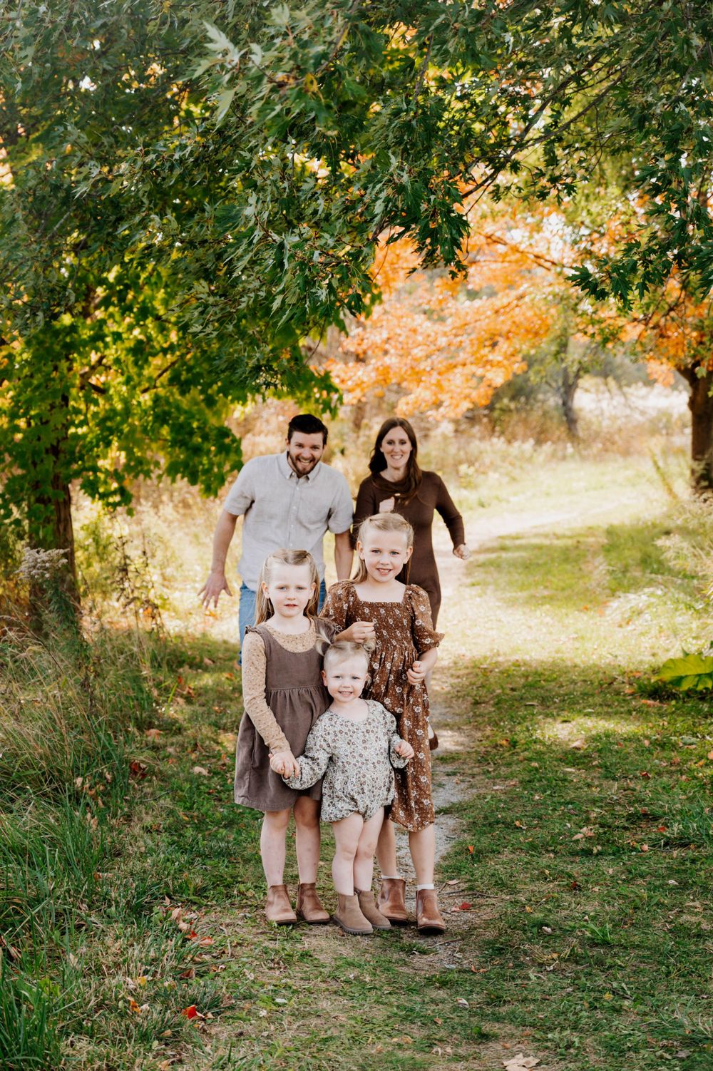 Family walking together on an autumn path with fall foliage in the background.