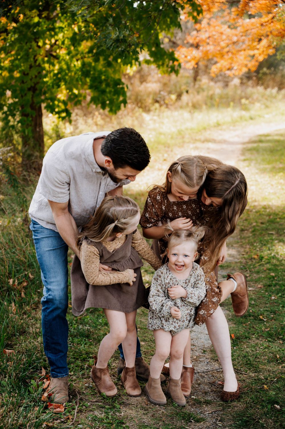 Candid family moment captured on a woodland path during autumn.