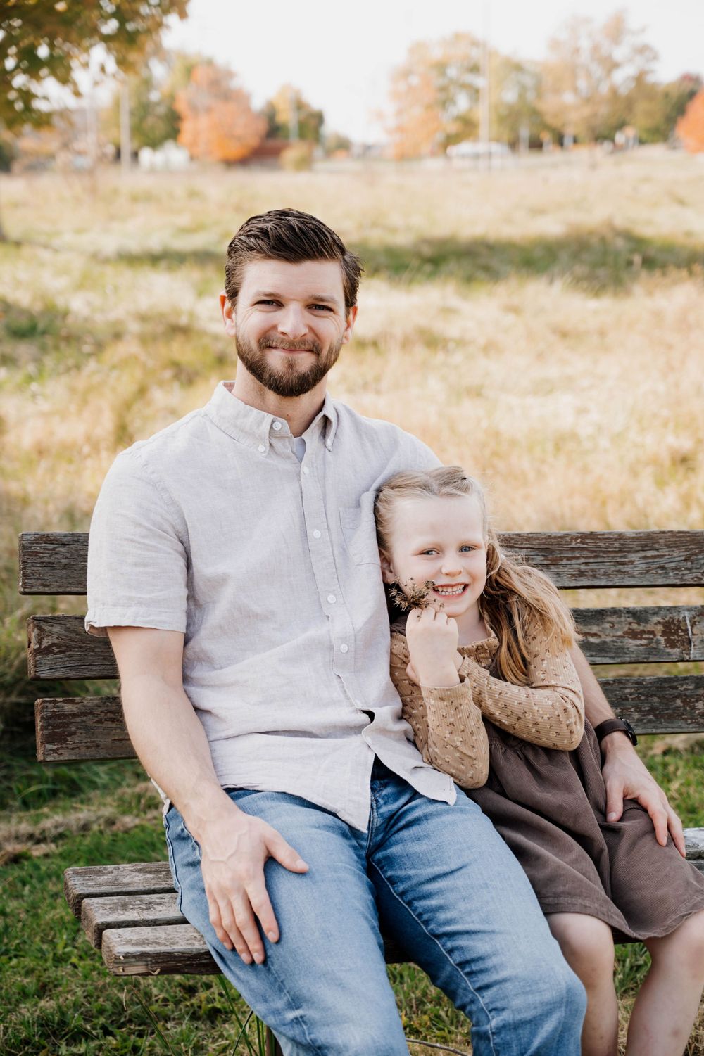Parent and child sharing moment on rustic wooden bench in outdoor setting.