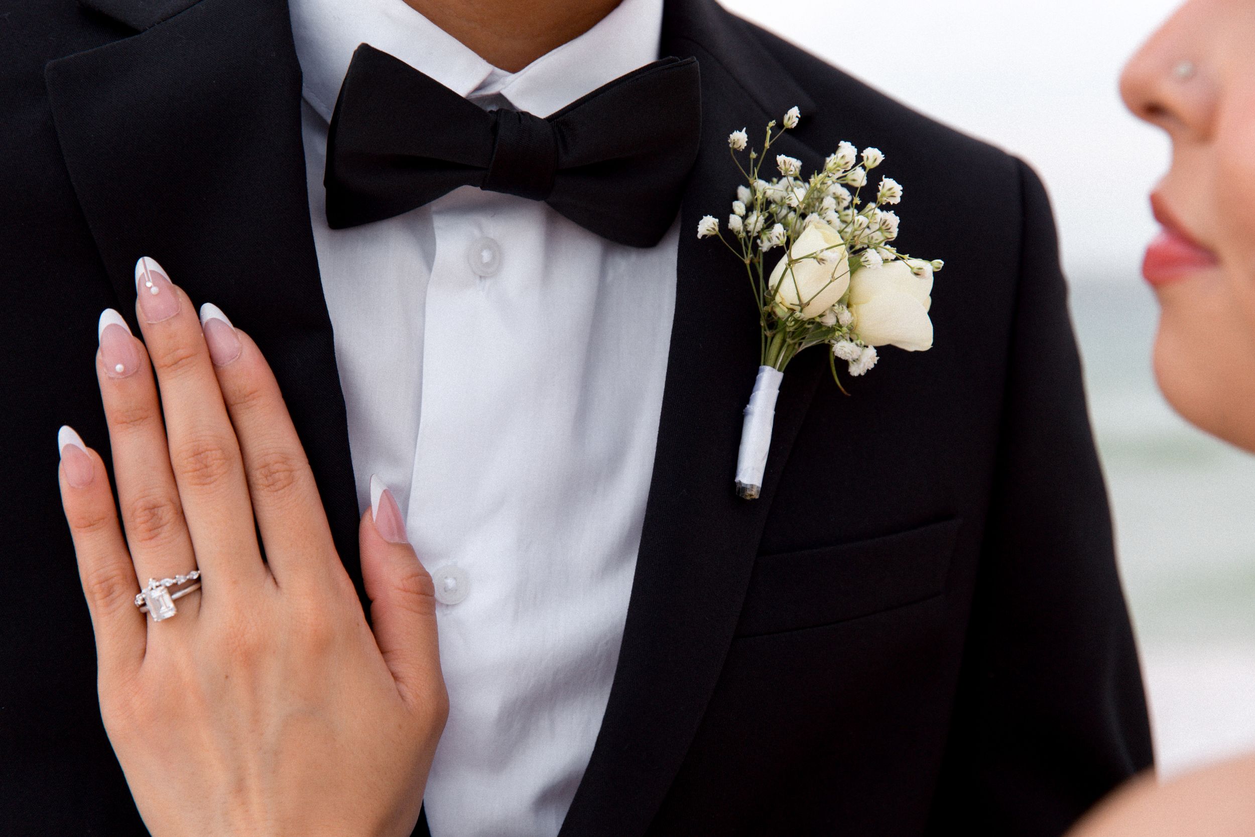 Close up of wedding attire showing boutonniere and bride's ring.