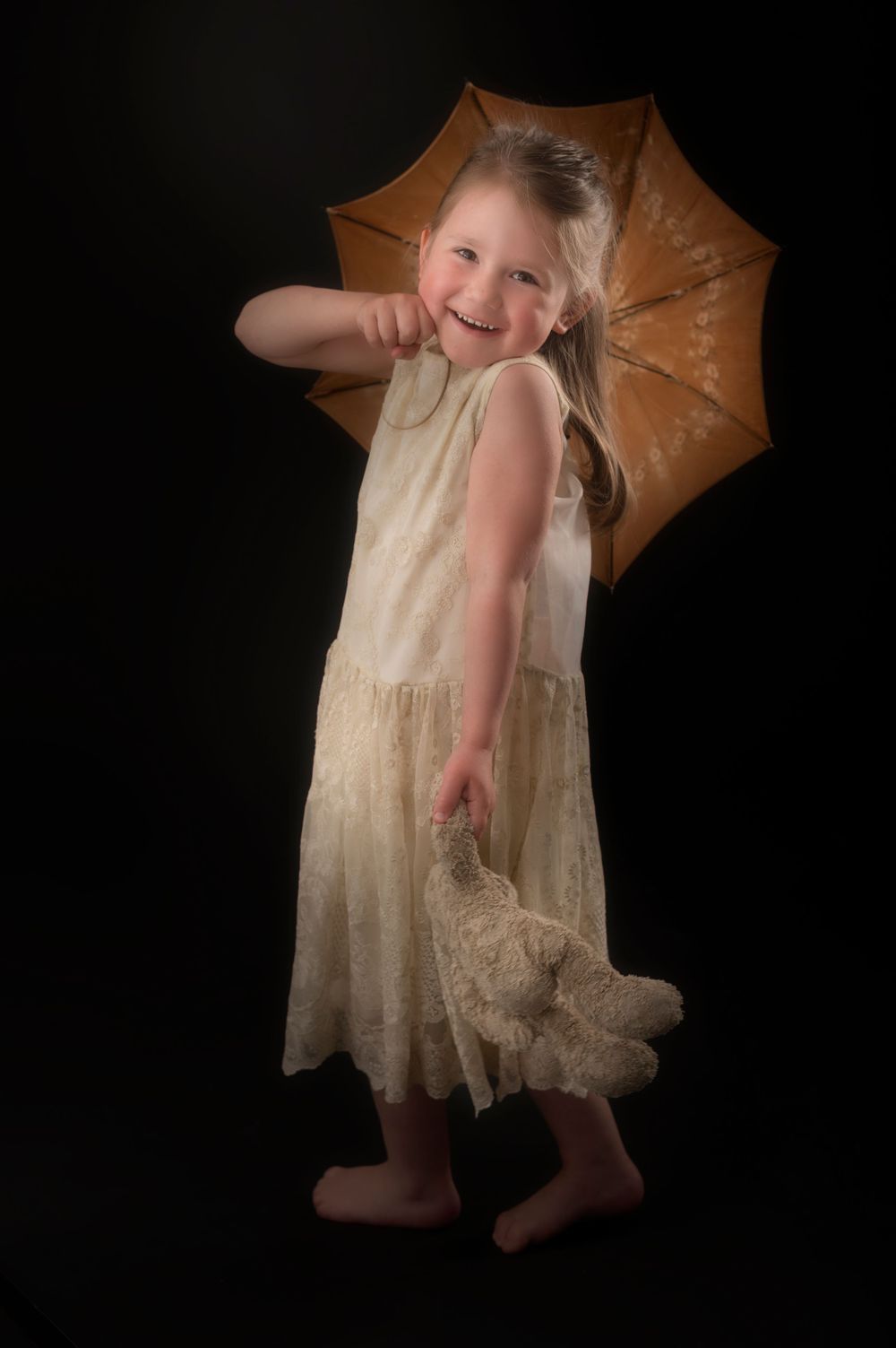 A vintage-style portrait with cream dress and parasol against dark background.