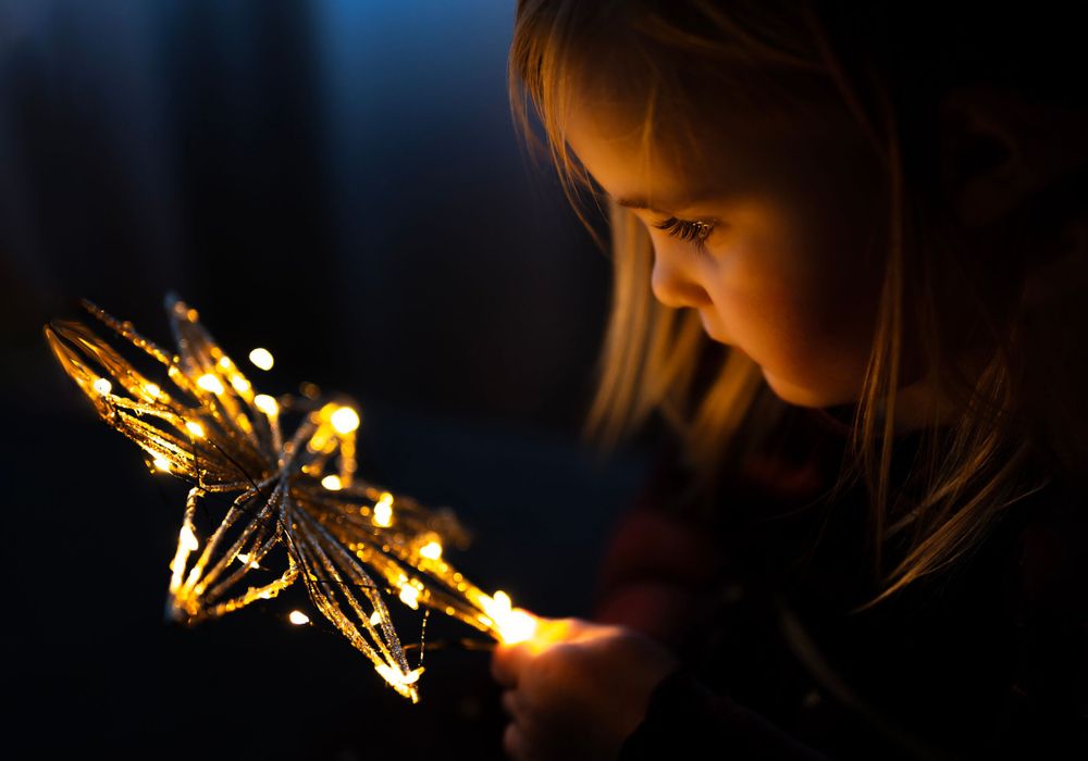 An intimate portrait with glowing golden star decoration in dark lighting.