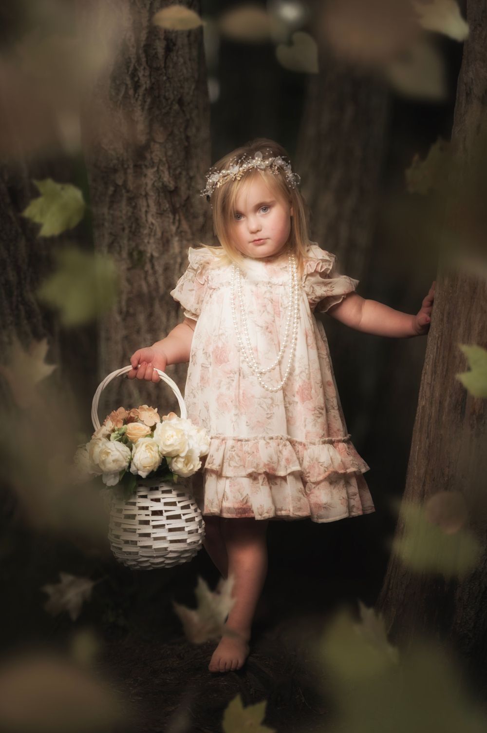 A dreamy portrait of a vintage-styled dress and basket of flowers in a forest setting.