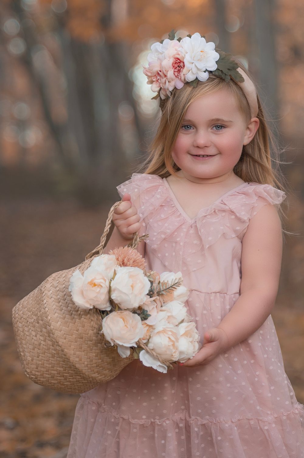 A whimsical autumn portrait featuring a pink dress and basket filled with pale roses.