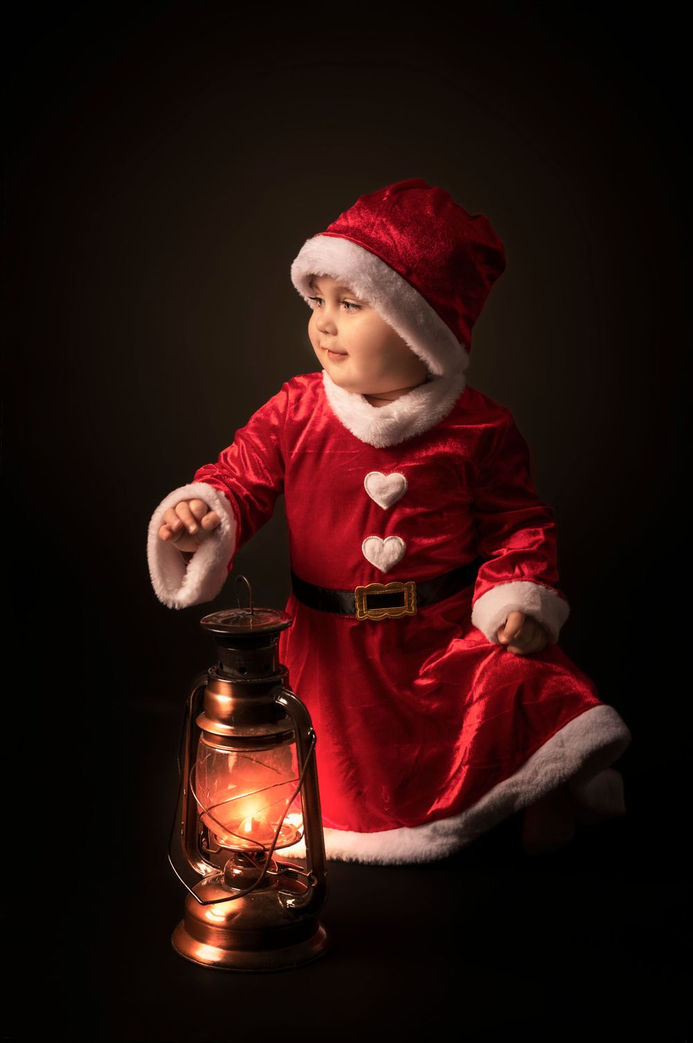 A festive holiday portrait with a glowing lantern and Santa-styled costume.