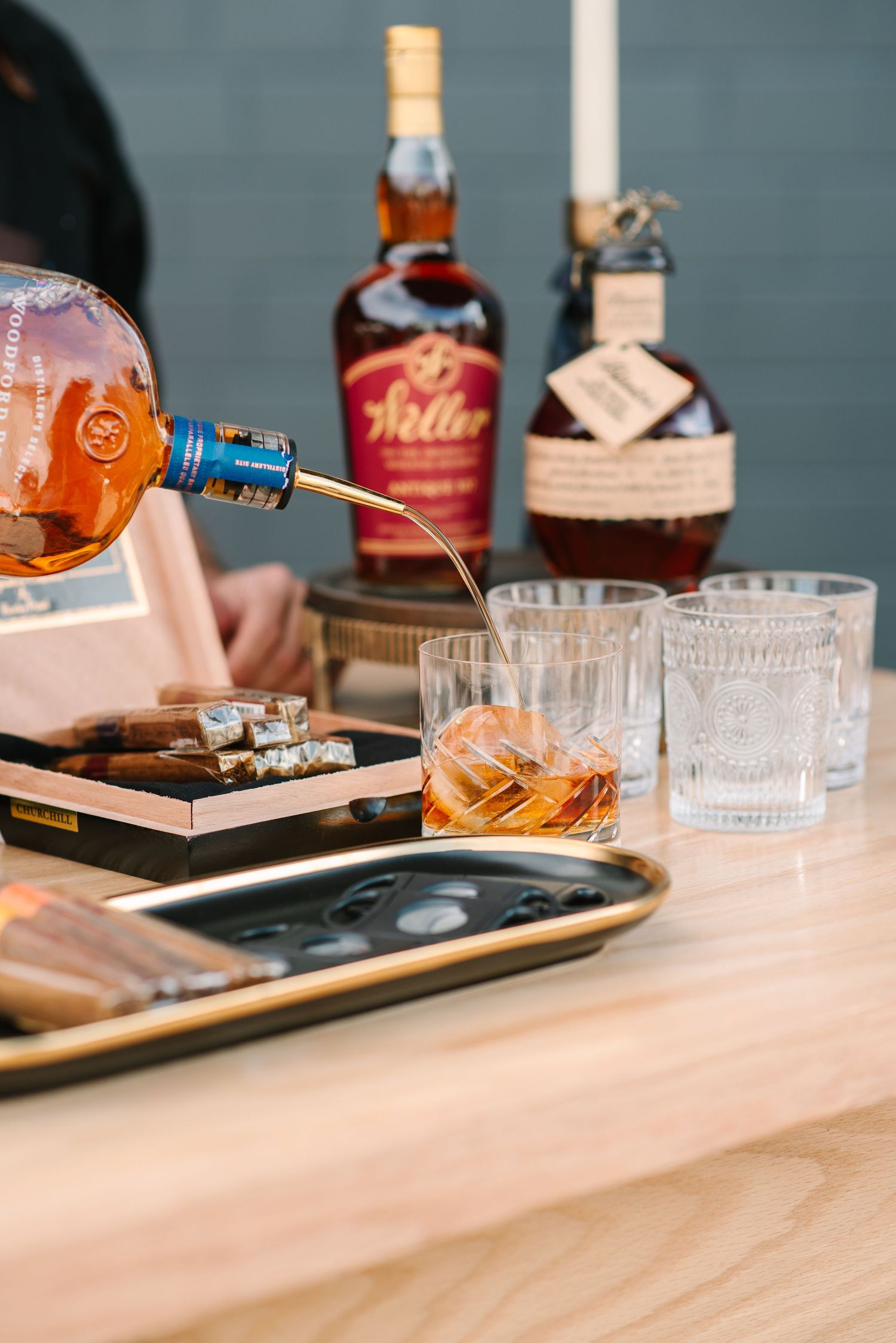 Wedding bar setup with whiskey bottles and crystal glasses on a wooden surface.