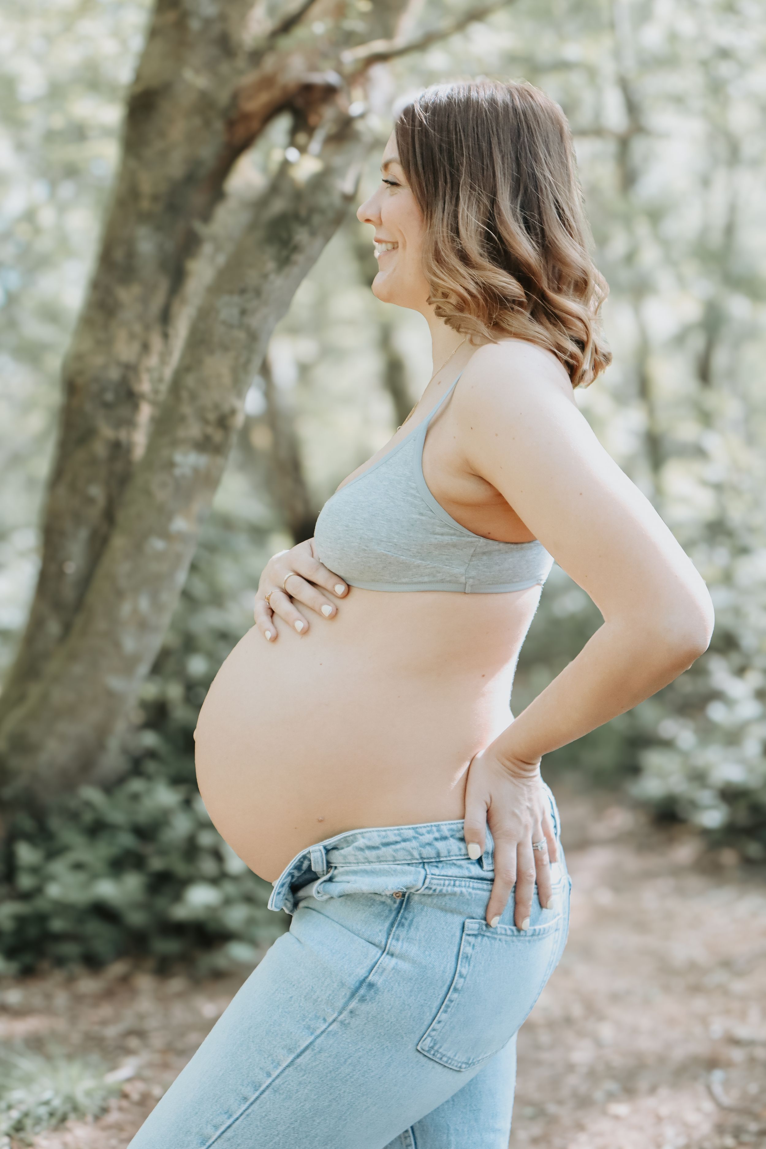 A maternity photoshoot showcasing a pregnant belly in light denim jeans.