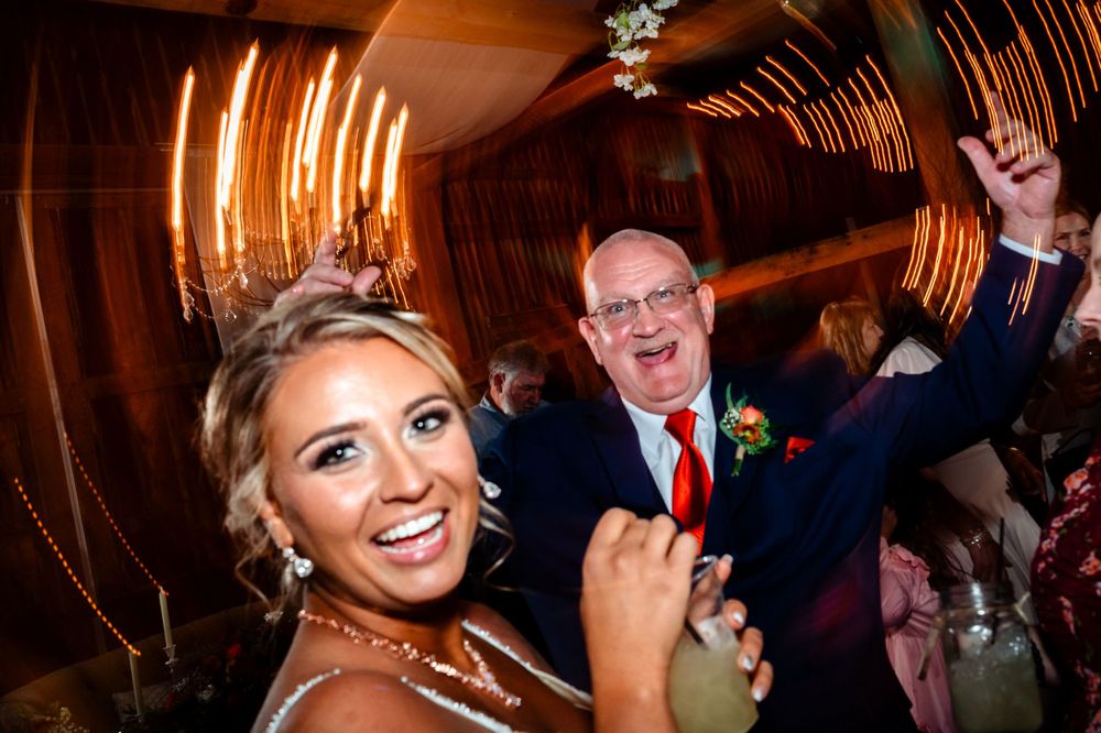 Joyful dancing and celebration captured during a wedding reception in a warmly lit venue.