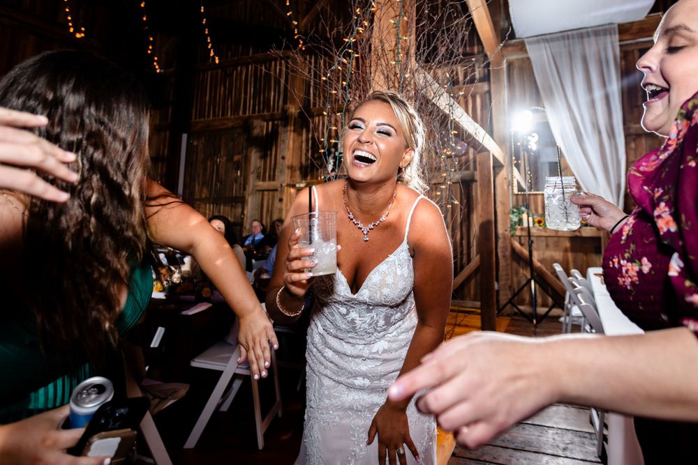 Lively dance party celebration in rustic barn venue with string lights.