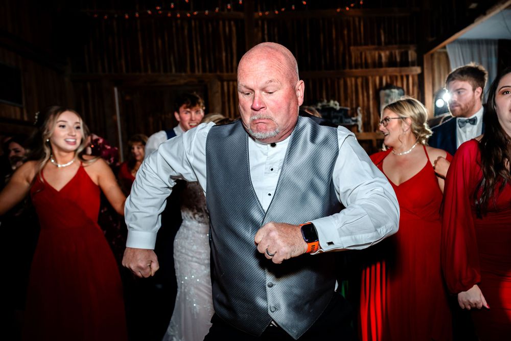 Wedding guests dancing and celebrating on a dimly lit dance floor at an evening reception.