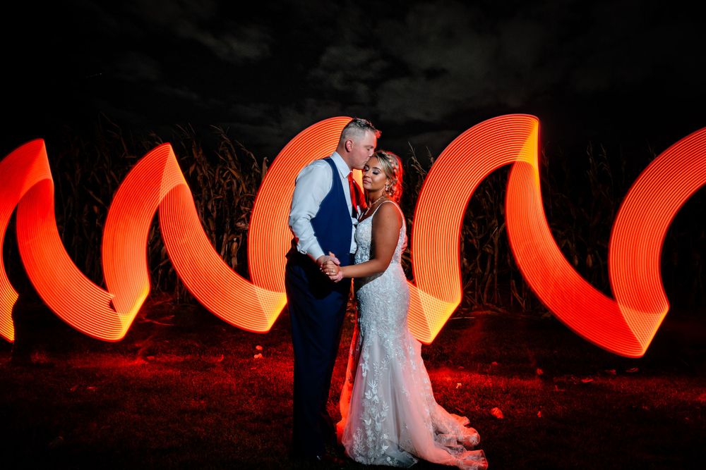 Dramatic nighttime wedding photos with glowing orange light trails creating artistic effects.