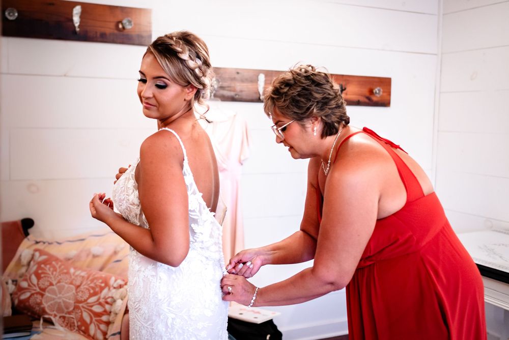 Bridesmaids in red dresses helping with wedding preparations indoors.