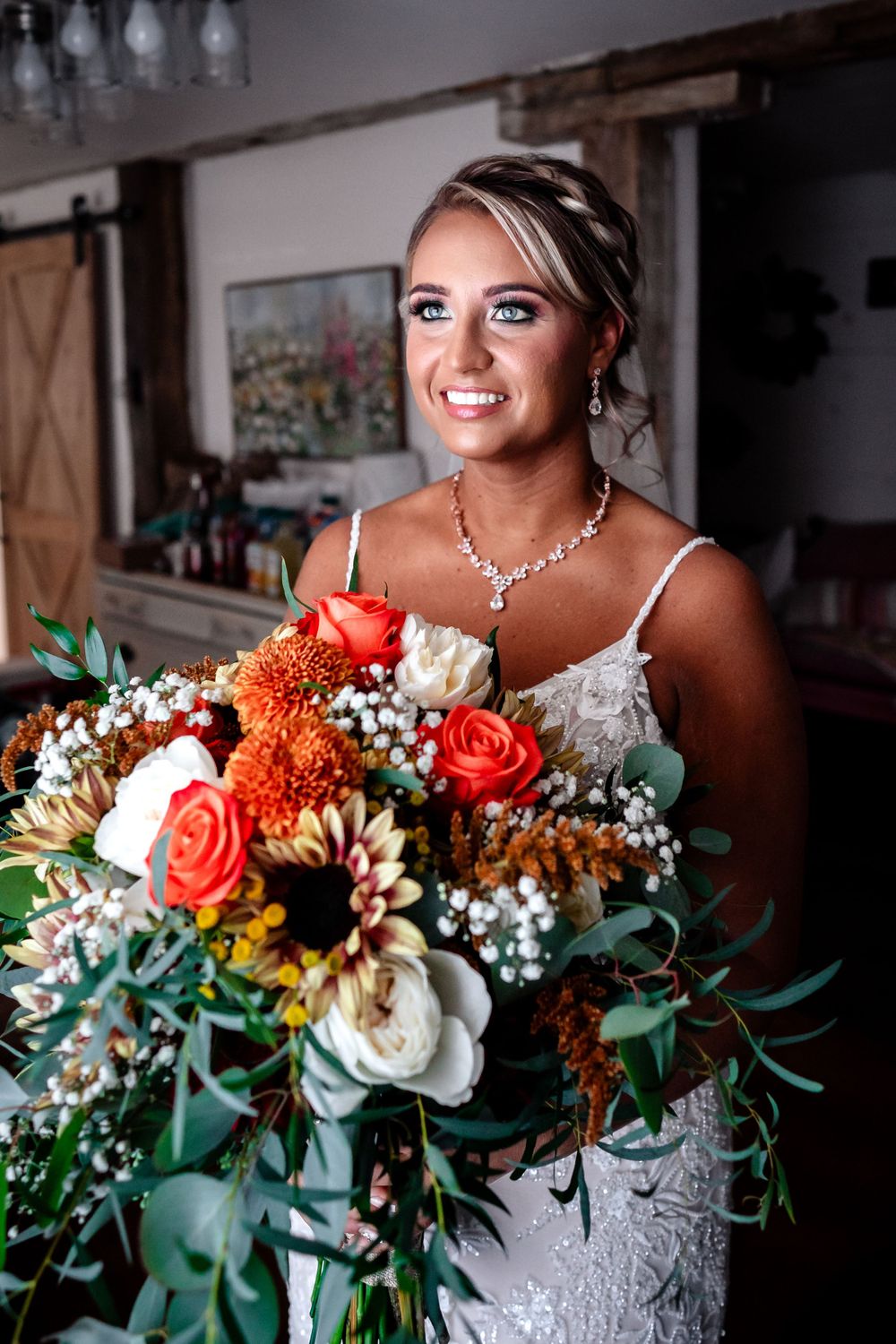 Wedding bouquet featuring orange roses, white flowers and greenery with bridal details.