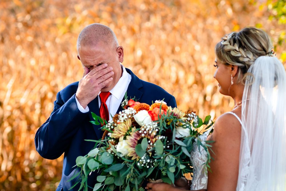 Wedding couple posing in front of autumn cornfield with golden light.