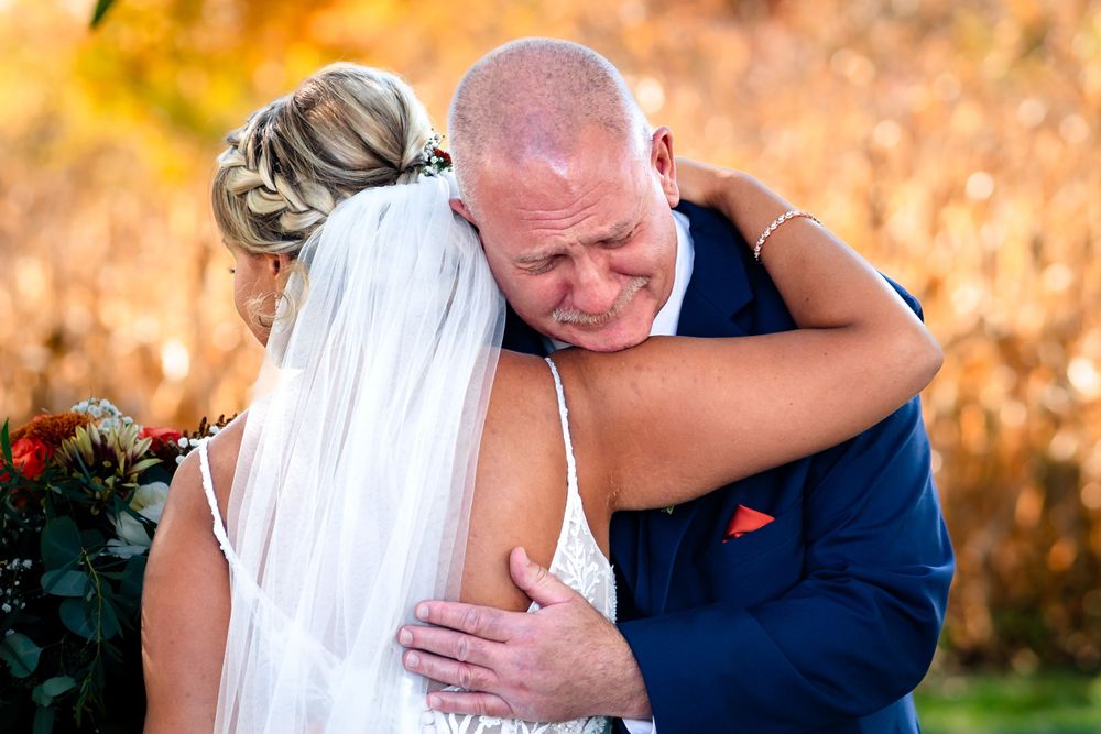 Emotional wedding moment captured against golden autumn backdrop.