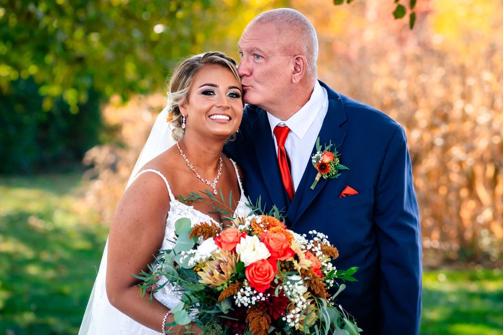 Wedding couple sharing intimate moment with bouquet in outdoor garden setting.