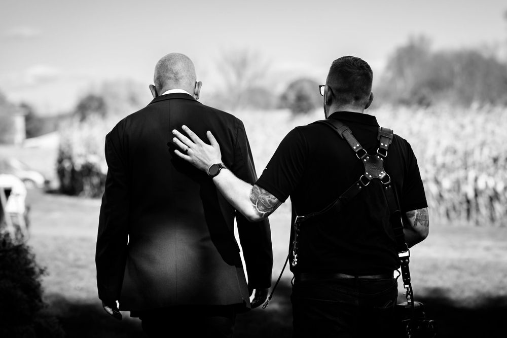 Silhouetted wedding couple embracing in dramatic outdoor lighting.